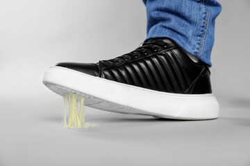 Man stepping into chewing gum on light grey background, closeup