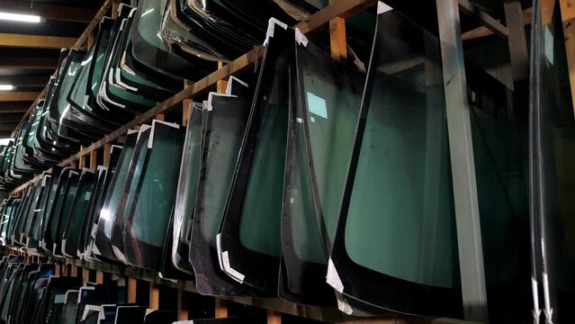 There are many different glasses for the car on the shelves of the car shop . New windshield and side windows on the shelves in the store. Salon for the replacement of car windows.