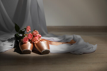 Ballet shoes. Elegant pointes and bouquet of roses on wooden floor indoors, space for text