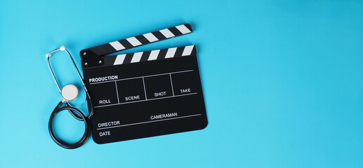 Clapper board or movie slate and stethoscope on blue background..