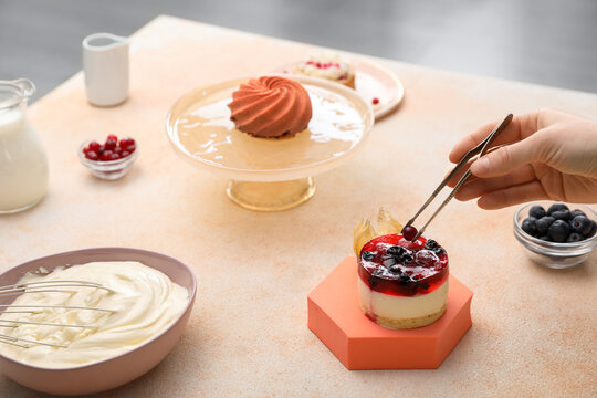 Food stylist creating composition with delicious dessert on table indoors, closeup