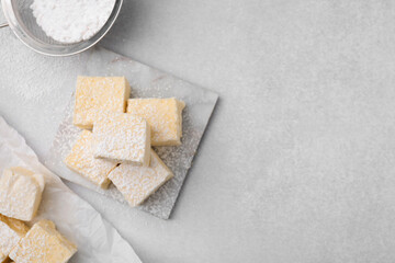 Delicious sweet marshmallows with powdered sugar on light grey table, flat lay. Space for text