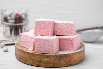 Tasty marshmallows with powder sugar on white textured table, closeup