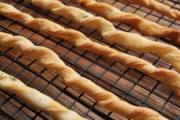 Rack with homemade breadsticks on wooden table, closeup. Cooking traditional grissini