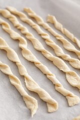 Homemade breadsticks on baking sheet, closeup. Cooking traditional grissini