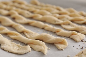 Homemade breadsticks with sesame on baking sheet, closeup. Cooking traditional grissini