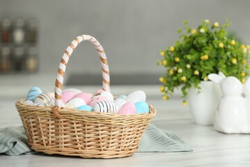 Fototapeta na wymiar Easter basket with many painted eggs on white marble table