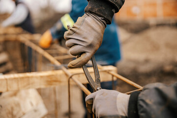 Close up of a construction site worker making foundation with pliers.