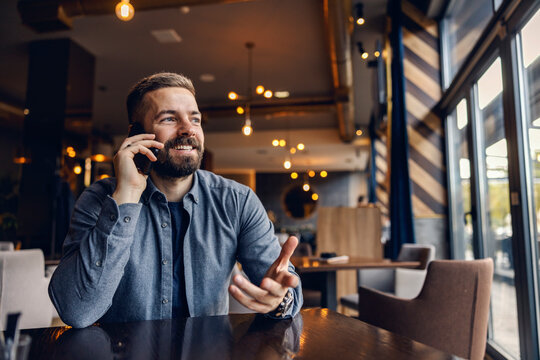 A man is sitting in cafe and having phone call.