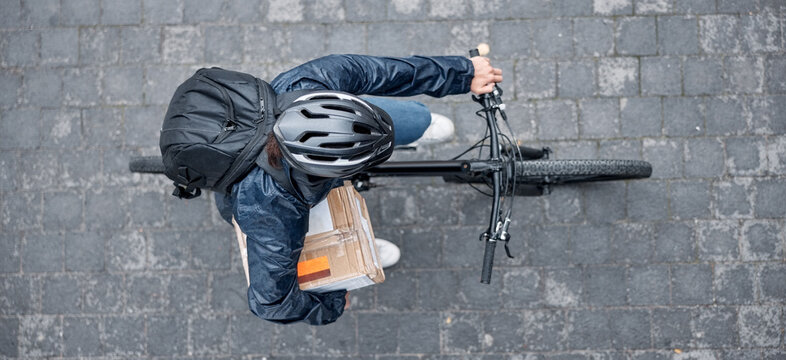 Top view, bicycle and delivery man with box in city for package, logistics and shipping. Courier, eco friendly transport and male bike driver with cargo, stock or goods for ecommerce on road in town.