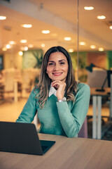 Portrait of a smiling woman, working over the laptop at the workplace.