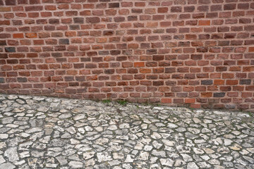 an old stone road running along a red brick wall