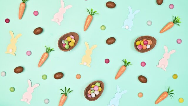 Creative Easter pattern with chocolate eggs, rabbits and carrots move on bright blue background. Flat lay. Stop motion