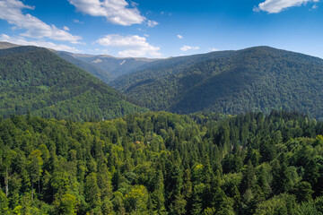 Fototapeta na wymiar Aerial view of Bucegi Mountains and Transbucegi waving road on top of them. Landmarks of Romania, beautiful sunny summer day.
