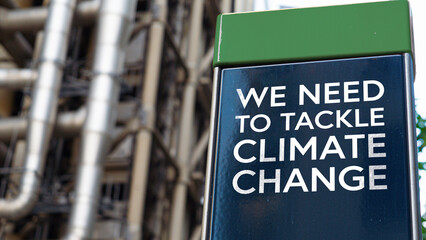 We need to tackle climate change on a sign in front of an Industrial building	