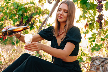 Young blonde woman sitting on a picnic in a vineyard