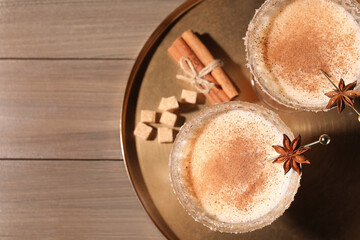 Delicious eggnog with cinnamon and anise on wooden table, flat lay. Space for text