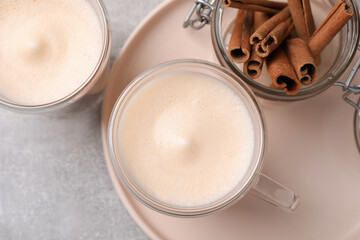 Delicious eggnog with cinnamon on light grey table, flat lay
