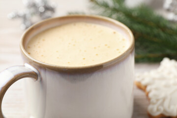 Cup of delicious eggnog on table, closeup