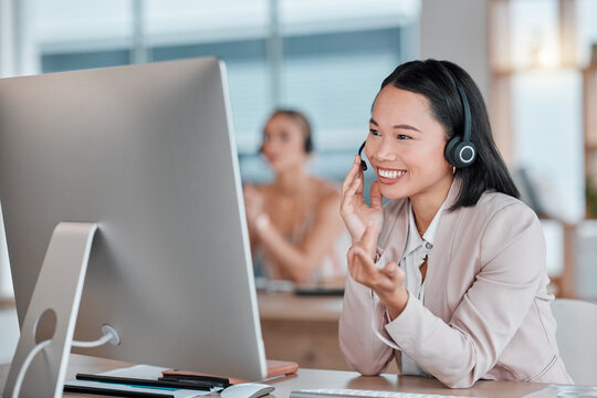 Asian woman, call center and computer with smile for telemarketing, customer support or service at office desk. Happy female consultant agent smiling in contact us for desktop advice, help or sales