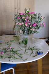 A bouquet of small pink carnations with eucalyptus in a vase on the table.flowers on the florist's table in flowershop. Work of the florist at a flower shop. Delivery fresh cut flower.