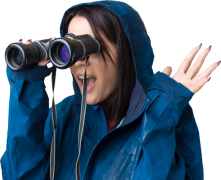 A tourist girl in a blue raincoat holds binoculars in her hands and looks into the distance, spies. - Powered by Adobe