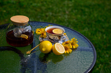 Hot herbal tea in a glass teapot and a cup with lemon. beautiful glass table. Tea drinking concept. Summer tea. Morning ritual.