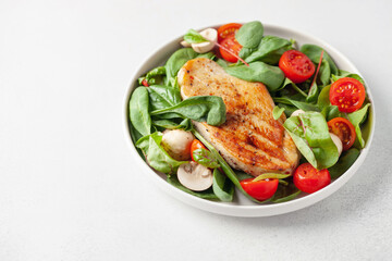 Fresh salad - spinach leaves, tomato, mushrooms, chards leaves and chicken fillet grill in a plate on the table. Healthy diet food.