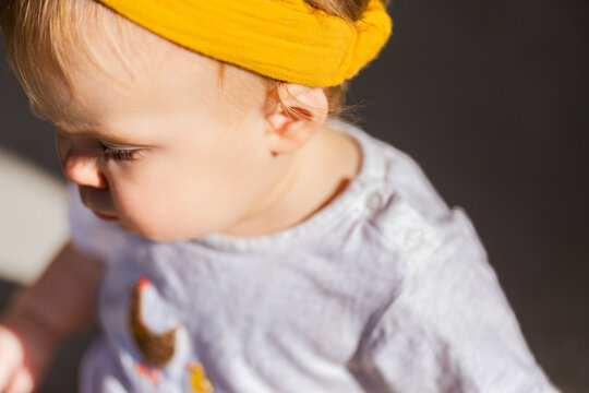 detail of baby face with yellow headband and ear in sunlight outside