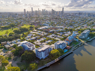 Aerial view of apartment buildings on a river bank with a city skyline in the distance