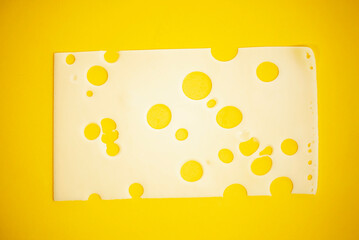 slice of cheese with holes on a yellow background close-up