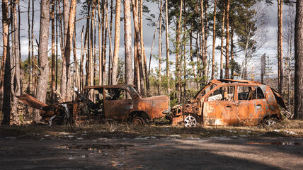 The war in Ukraine, burnt civilian cars, destroyed cars are standing on the road, front  view,...