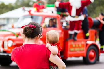 Mum holding baby to see the lolly run fire truck with Santa at Christmas time