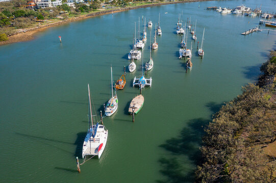 Aerial view of yachts anchored in lines on a calm coastal bay