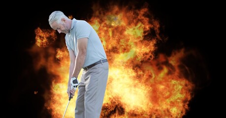 Caucasian senior male golf player holding club against fire flame effect on black background