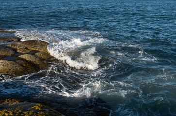 Surf on the coastline of the north sea with a mountainous coast in the background