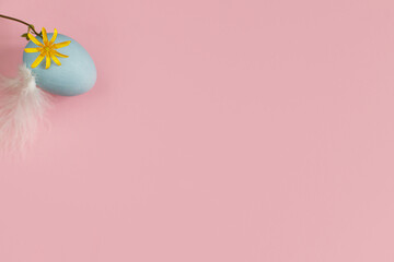 Happy Easter! Easter egg and blossom on pink background flat lay. Minimal Easter still life. Modern spring banner or greeting card, space for text. Natural blue egg, feather and flower