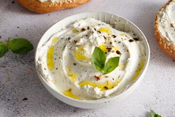 Cheese curd spread for breakfast with herbs, sun-dried tomatoes and olive oil close-up