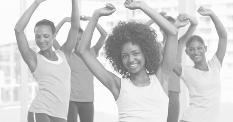 Composition of group of happy women exercising in fitness class in black and white