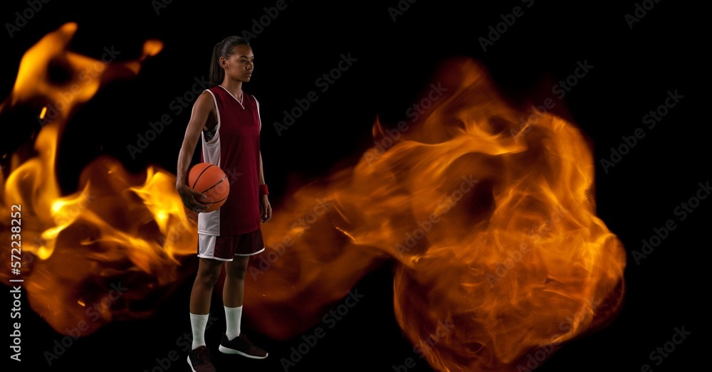 Canvas Prints Composition of male basketball player standing holding ball over flames on black background