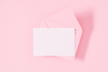 Top view on open pink envelope with paper card on pastel pink table background. Birthday, Wedding, Mother's Day, Valentine's day, Women's Day. Flat lay, copy space