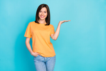 Portrait of cheerful pretty girl arm palm hold empty space proposition isolated on blue color...