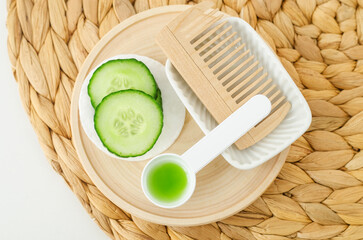 Cucumber slices, cucumber juice and wooden hairbrush. Ingredients for preparing homemade face toner or beauty mask. Natural skin care or hair treatment and spa recipe. Top view.