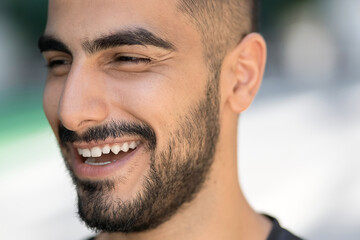Obraz premium Portrait of happy confident middle eastern man laughing and looking away on the street, selective focus. People and emotions concept 