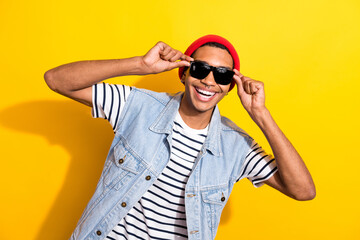 Photo of overjoyed satisfied person toothy smile hands touch sunglass isolated on yellow color background
