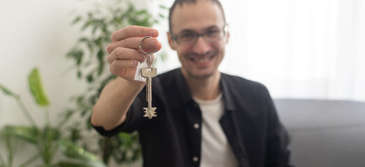 Portrait of handsome young man holding keys from house or auto on the white background.