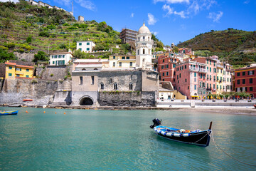 View on bay of water with moored boats and typical colorful houses in small village, Riviera di Levante, Vernazza, Cinque Terre, Italy