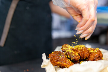 woman chef cooking chicken wings in a sauce in the kitchen