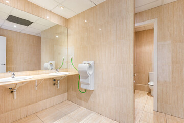Public toilet with big mirror, handwashers, dryer and wc doors.