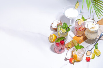 Summer cocktails drinks. Classic alcoholic long drink mocktail versions, various beverages, lemonades with berries, lime, orange, coconut, ice on white marble background 